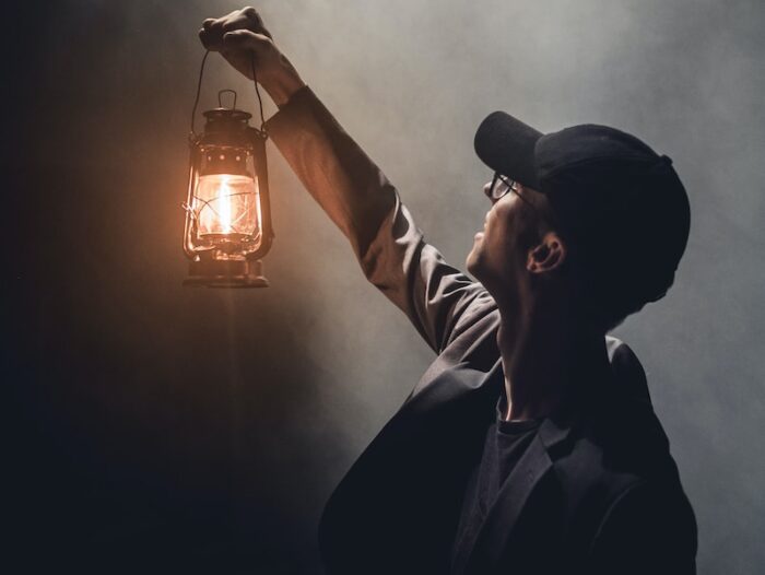 man holding lighted gas lantern