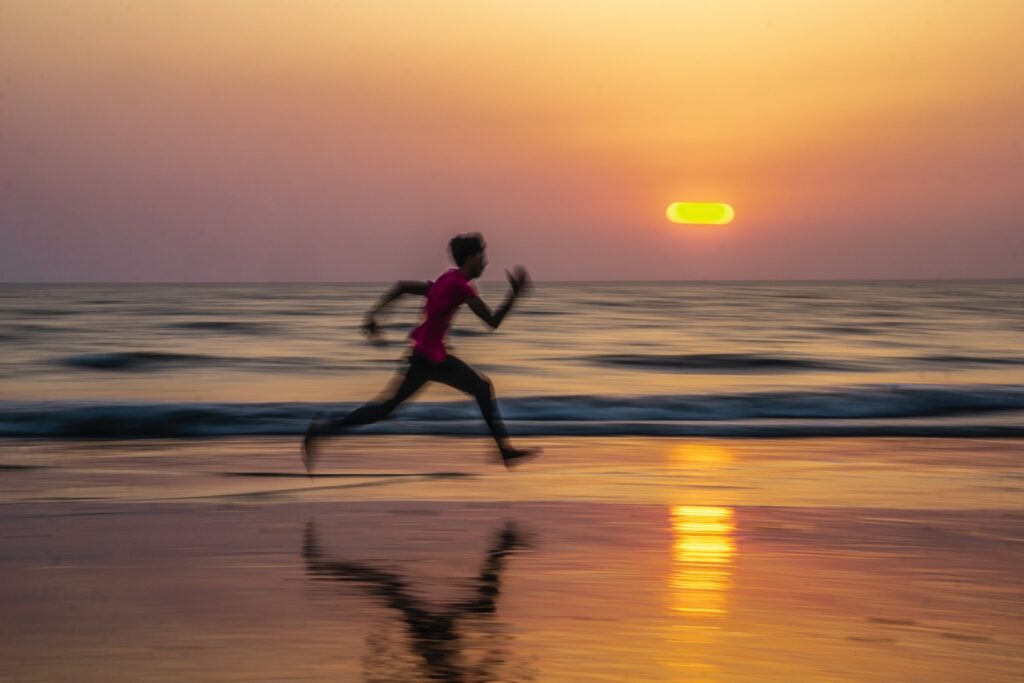 man running along seashore during golden hour