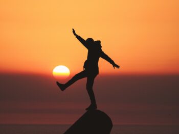 photo of silhouette photo of man standing on rock
