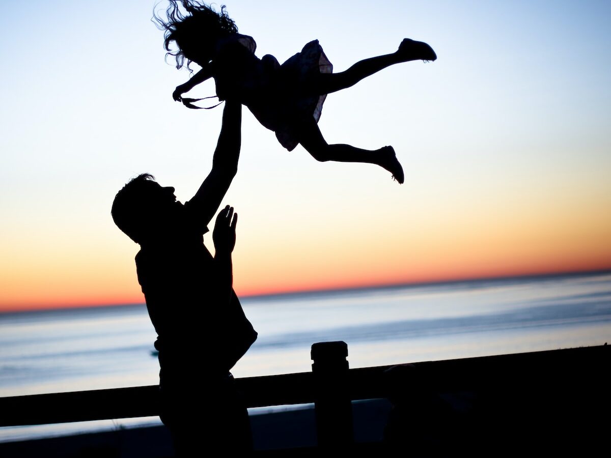 silhouette of man throwing girl in air