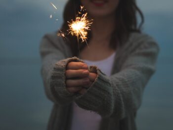 focus photo of a woman holding sparklers
