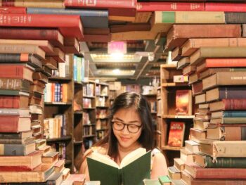 woman in green shirt sitting on books