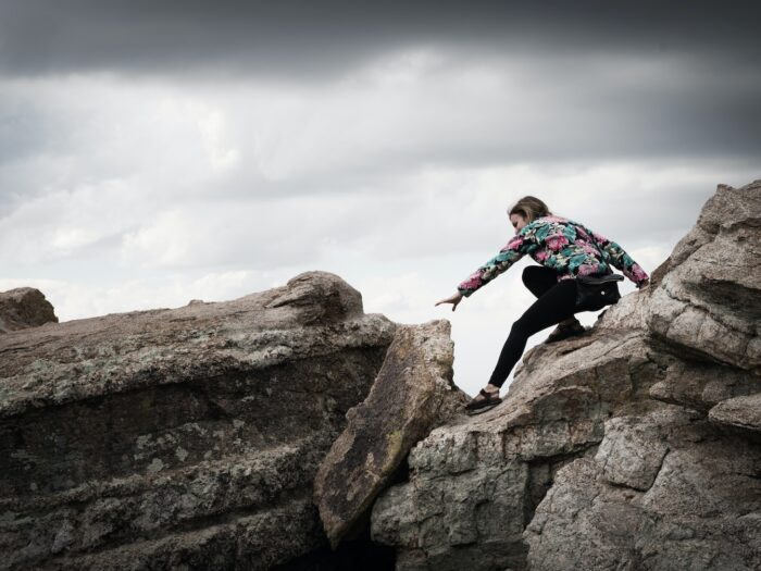 woman climbing on rocks during daytime photography